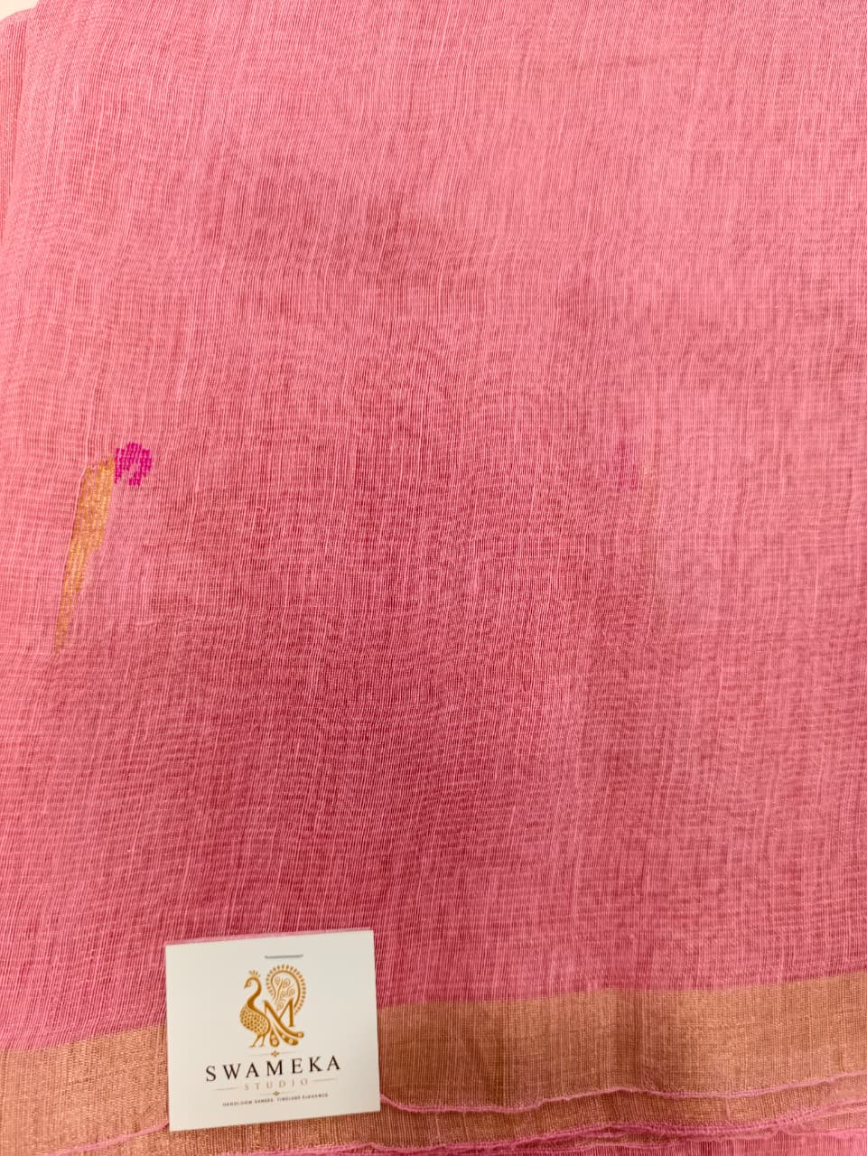 Elegant pastel pink Tissue Linen Jamdani saree with Paithani-style handwoven parrot motifs and delicate golden zari detailing.