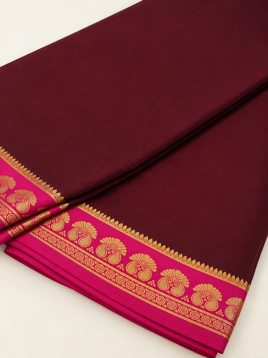 Elegant wine-maroon Mysore Crepe silk enriched with traditional gold zari and graceful twin-peacock-inspired border motifs.