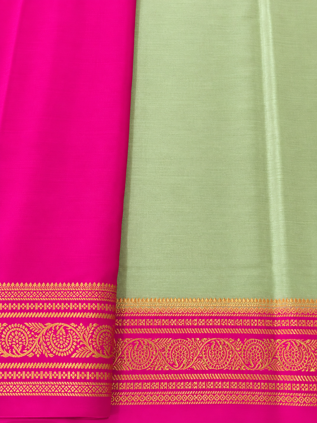 legant pastel green Pure Mysore Silk Crepe with a vibrant Rani Pink pallu and intricate floral gold zari borders.