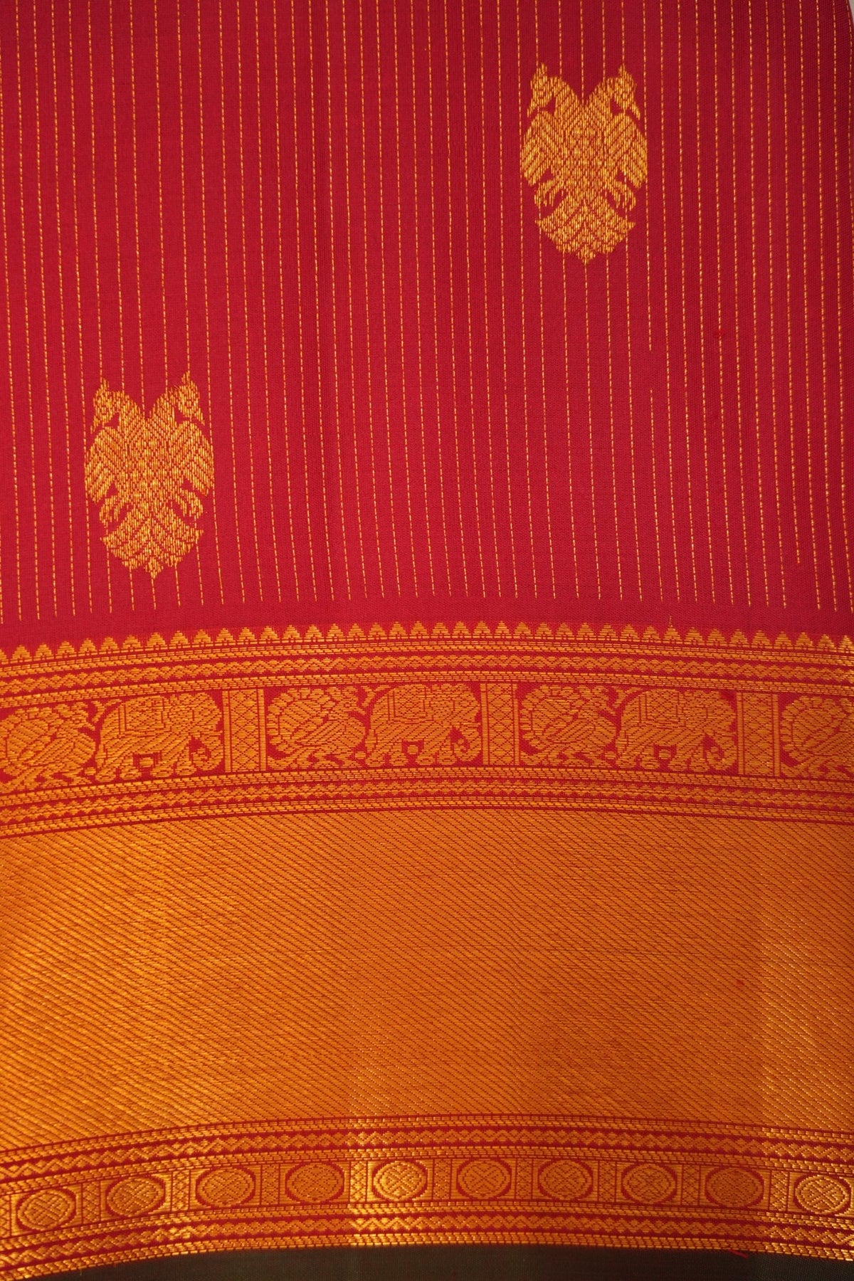 Rich deep crimson red Kanjivaram silk adorned with Gandaberunda motifs, peacocks, elephants and Rudraksha zari detailing.
