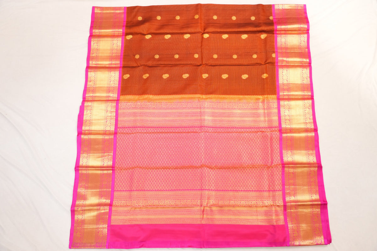 Warm Terracotta Sienna Kanjivaram silk with rich Magenta, featuring Peacock and Rudraksha motifs framed by elegant running leaf zari borders.