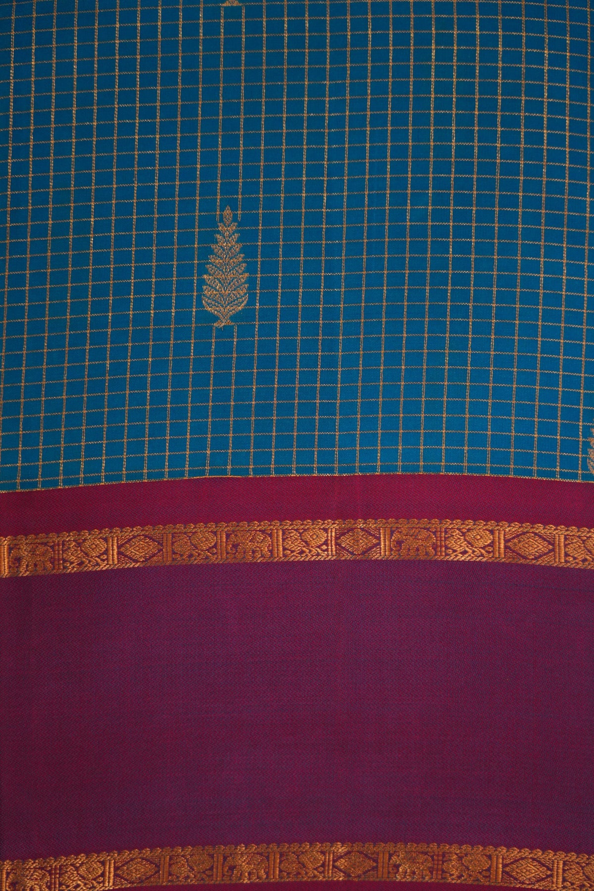 Vibrant turquoise blue Kanjivaram silk with gold zari checks and leaf motifs, complemented by magenta and a traditional elephant, peacock & diamond zari border.