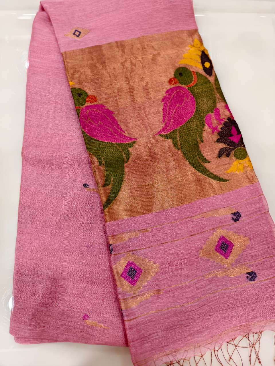 Elegant pastel pink Tissue Linen Jamdani saree with Paithani-style handwoven parrot motifs and delicate golden zari detailing.