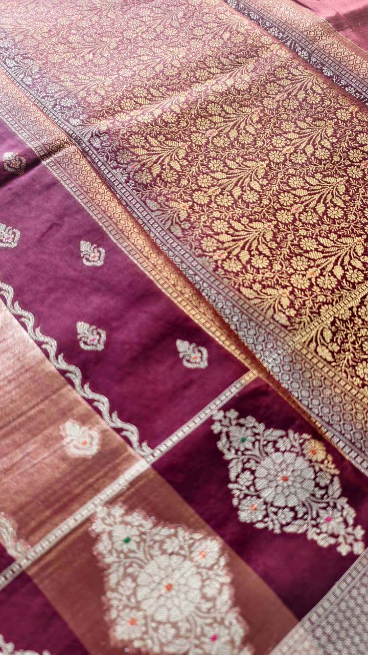 A luxurious Banarasi viscose silk saree in a rich deep wine-maroon shade, featuring intricate traditional motifs and elegant metallic-toned borders.