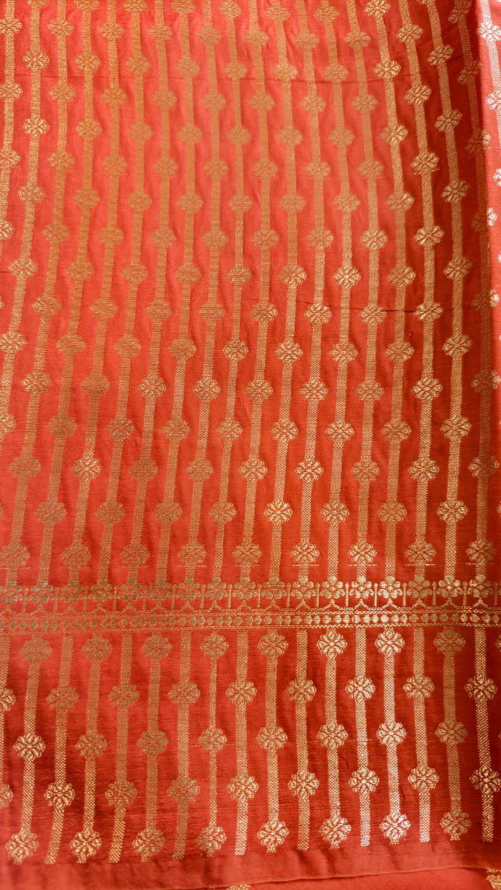 A vibrant Coral Orange Banarasi viscose silk saree featuring delicate traditional butis, intricate floral motifs and elegant Minakari weaving. The warm coral-orange base beautifully complements the metallic and colourful detailing,