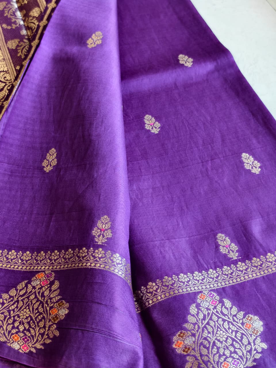 A regal Purple Banarasi viscose silk saree featuring intricate Minakari weaving, delicate traditional butis and an ornate floral pallu.