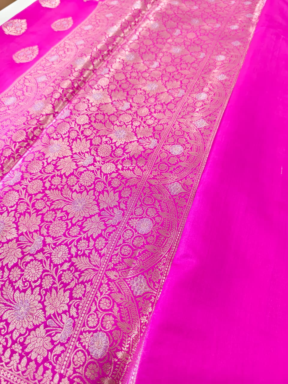 A rich Rani Pink Pure Silk Mark Certified Katan Chiniya Silk Banarasi saree, featuring intricate traditional Banarasi weaving and elegant motifs.