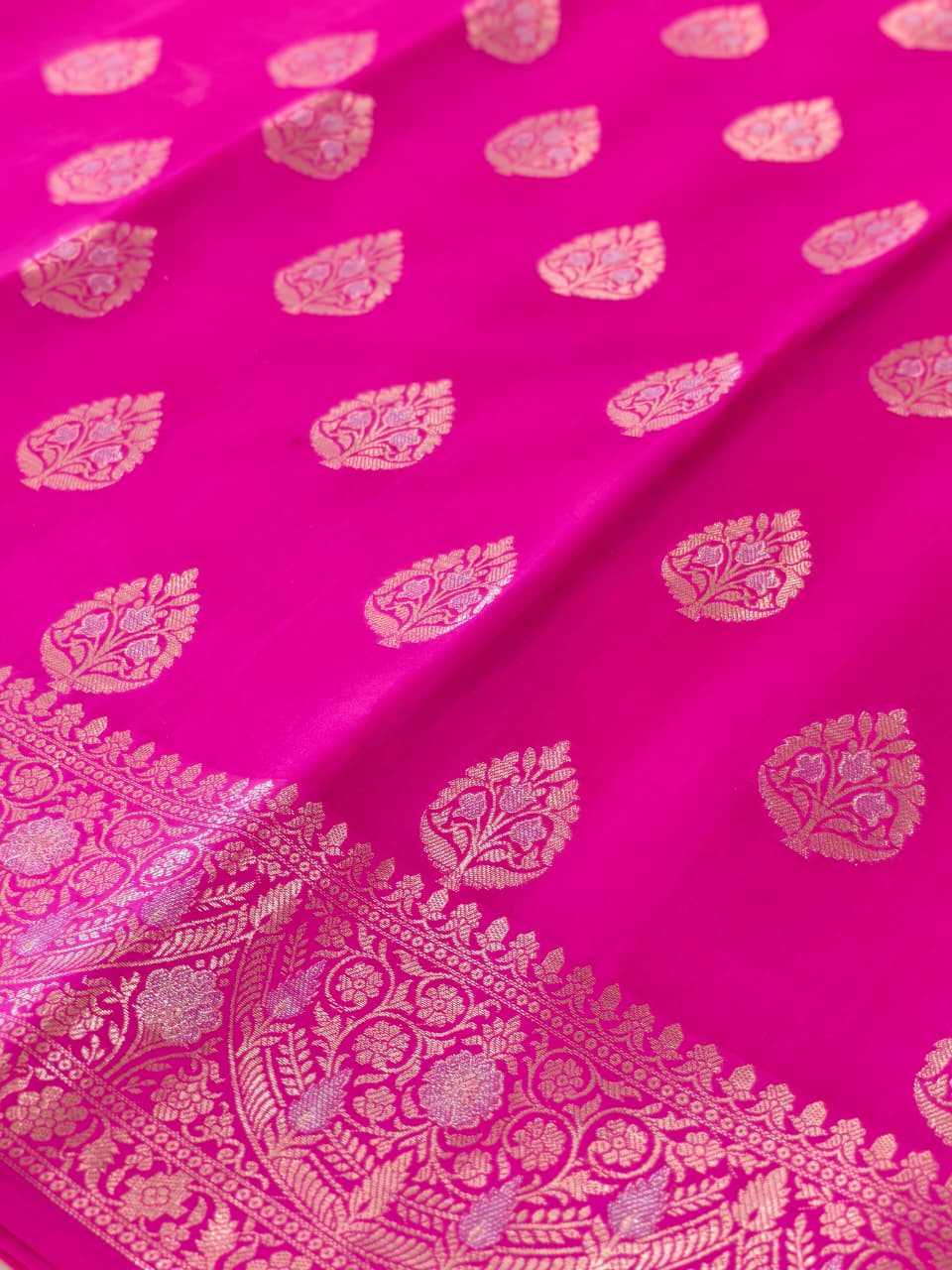A rich Rani Pink Pure Silk Mark Certified Katan Chiniya Silk Banarasi saree, featuring intricate traditional Banarasi weaving and elegant motifs.