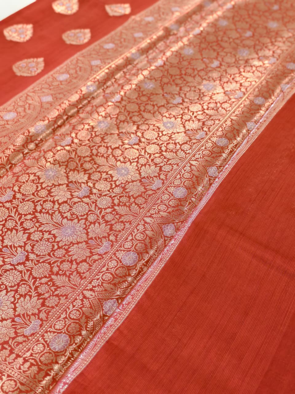 A rich Ruby Red Pure Silk Mark Certified Katan Chiniya Silk Banarasi Saree, featuring intricate traditional Banarasi weaving and elegant Chiniya-inspired motifs.