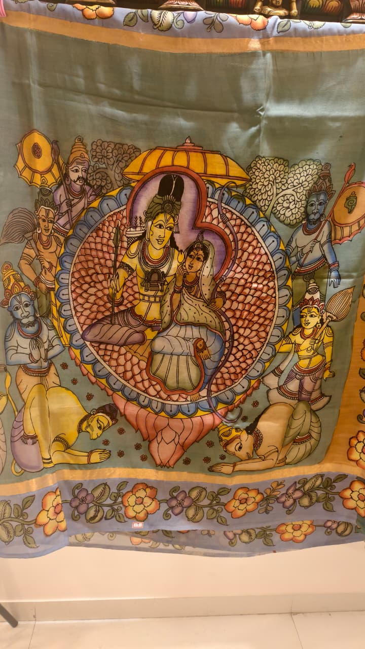 Hand-painted Kalamkari saree in Bangalore Silk featuring Rama & Sita on the body, Krishna & Radha on the pallu, floral borders, and a matching lavendar lotus-motif blouse piece