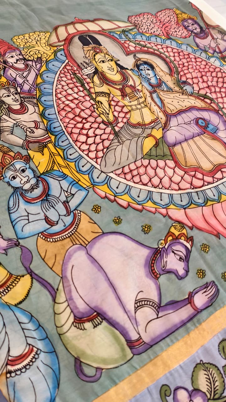 Hand-painted Kalamkari saree in Bangalore Silk featuring Rama & Sita on the body, Krishna & Radha on the pallu, floral borders, and a matching lavendar lotus-motif blouse piece